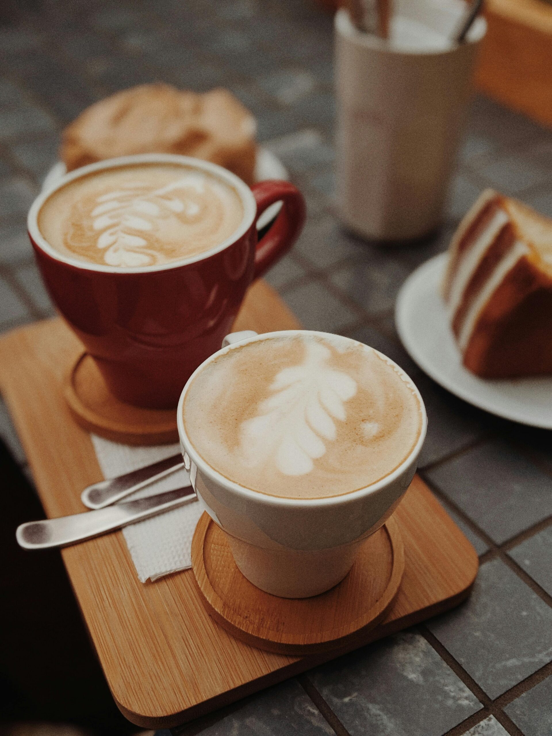 Delicious latte art accompanied by a slice of cake on a cafe table.