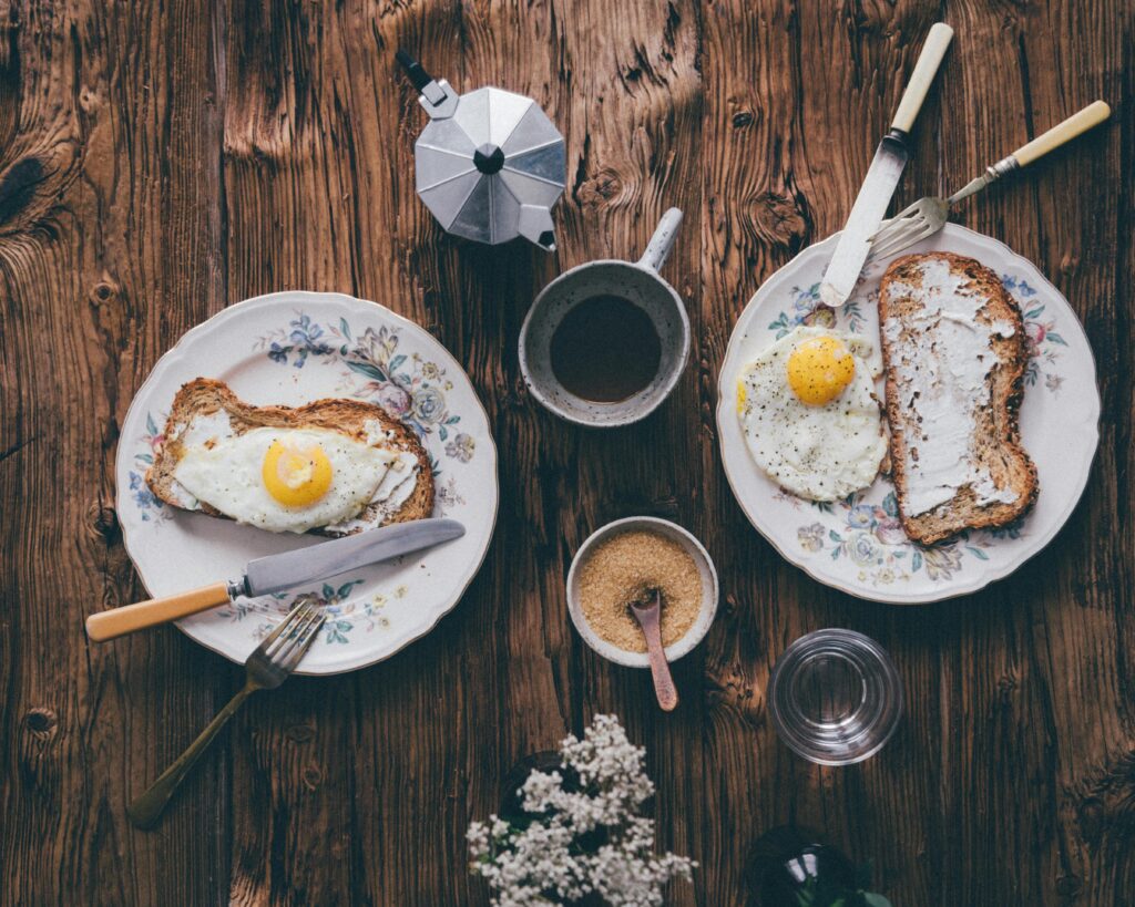 pexels-photo-5720787-5720787 Vintage-style flat lay of breakfast with eggs, toast, and coffee on a wooden table.